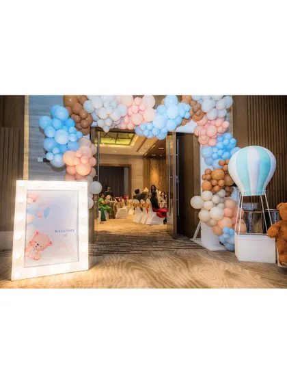 A grand entrance for a teddy bear party, featuring a large balloon arch in pastel colors and a light-up welcome sign.