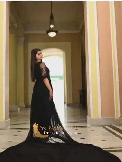 The black trail gown is captured from behind in a grand hallway, emphasizing the length of the tail and creating a sense of drama and mystery.