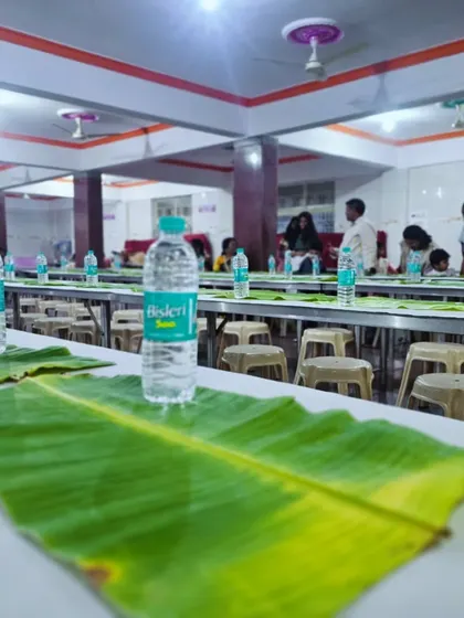 The dining hall at ANR Bhavan, set up with fresh banana leaves and water bottles, ready for guests to arrive.