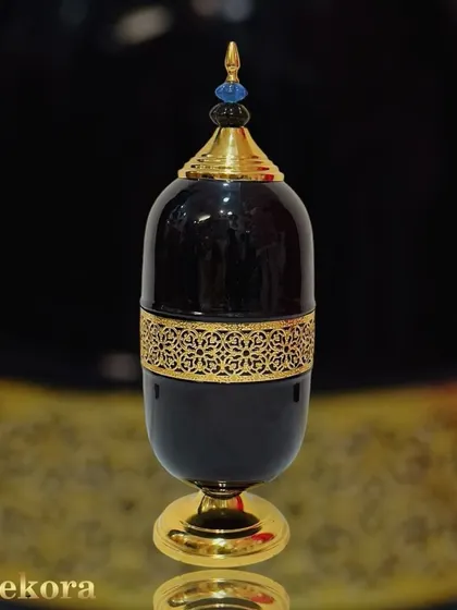 A close-up of the black and gold luxury metal showpiece. The detailed craftsmanship is evident in the golden filigree band and the finial on the lid, highlighting the quality we deliver as manufacturers.