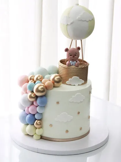 Sweet beginnings! This baby shower cake features a hot air balloon theme with a soft pastel balloon cascade, perfect for celebrating the upcoming arrival.