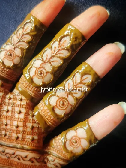 The fresh paste of the floral cut-work on fingers, highlighting the clean application.