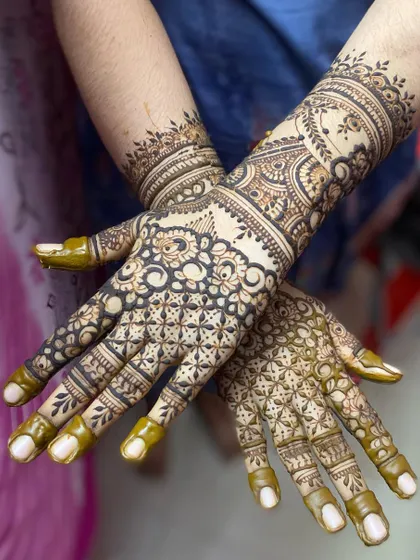 A beautiful example of a full-coverage design with fresh henna paste, showing the intricate grid work and floral patterns before the stain develops.