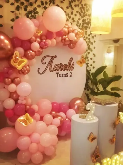 This simple round frame decor for Aarohi's second birthday features a beautiful pink and rose gold balloon garland with butterfly accents. Note: This is the same setup as ID 28, 82, 104.