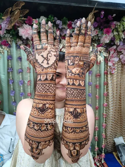 The bride proudly holding up her arms, a beautiful canvas of henna art.