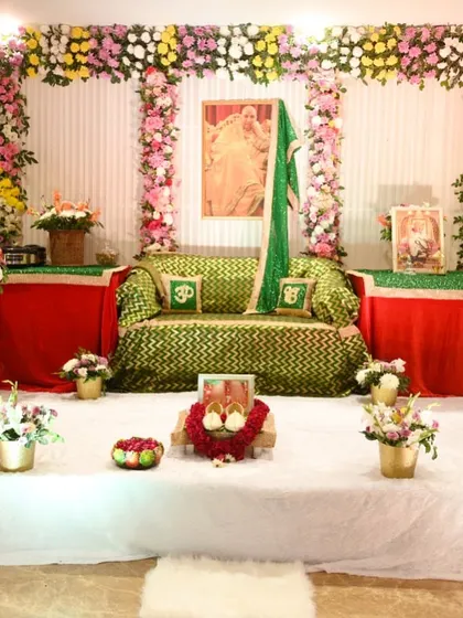 A serene and beautiful flower arrangement for a Guruji Satsang. The stage is decorated with columns of fresh flowers and a comfortable seating area.