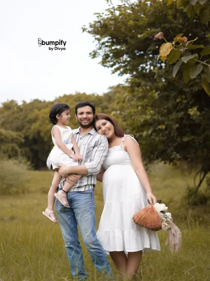 From three to four. An outdoor maternity shoot is a wonderful way to capture the whole family's excitement. This candid moment in a green field shows the joy of a growing family.