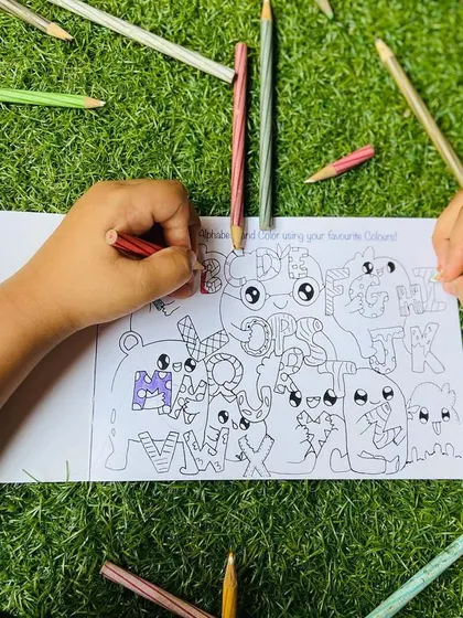 A close-up of little hands coloring in the alphabet doodle page from my book.