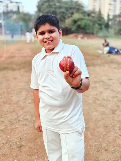 The unforgettable feeling of a first five-wicket haul. This young bowler proudly displays the match ball, a significant milestone for any aspiring cricketer that we celebrate together.