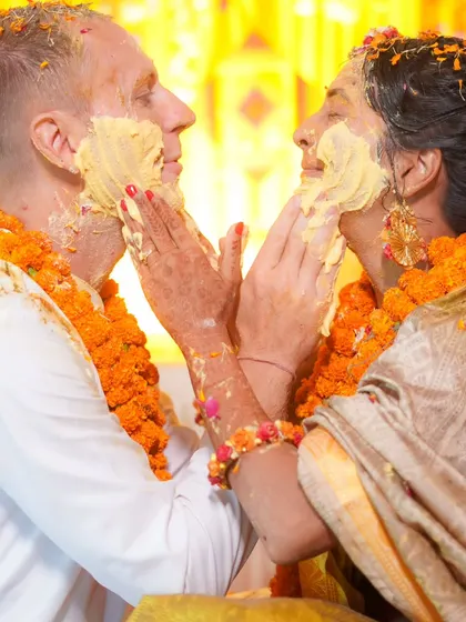 A tender moment amidst the fun. The couple gently applies haldi to each other, a sweet contrast to the usual chaos of the ceremony.