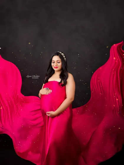 A dramatic fabric toss with a bold pink gown against a black background. The added sparkles give this powerful portrait a touch of magic.