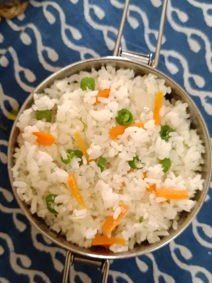 A serving of my simple vegetable fried rice, with peas and carrots, packed in a steel tiffin. It's a light and healthy option that pairs well with any of my curries.