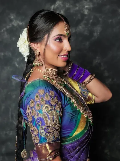 A profile shot of a model showcasing a stunning peacock-embroidered blouse. The vibrant colors of her saree and her happy expression make this a joyful and stylish portrait.