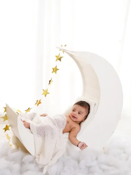 A six-month-old baby boy looking content and relaxed on our popular moon and stars prop. A perfect way to mark the half-year milestone.