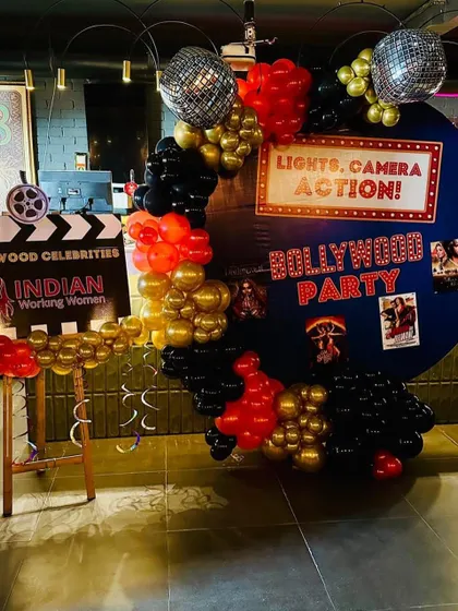 A Bollywood-themed party setup we designed. The backdrop features a "Lights, Camera, Action!" sign, a film clapboard, and disco balls, perfect for a fun and glamorous event.