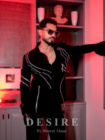Leaning against a wall under a red light, this shot captures the moody and sophisticated vibe of the zipper-detailed shirt.