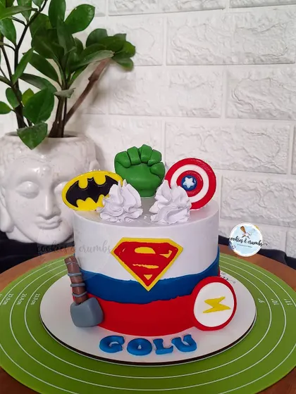Avengers assemble! This superhero themed cake brings together iconic symbols like the shields of Superman and Captain America, Batman's logo, and Hulk's fist for an action-packed birthday.