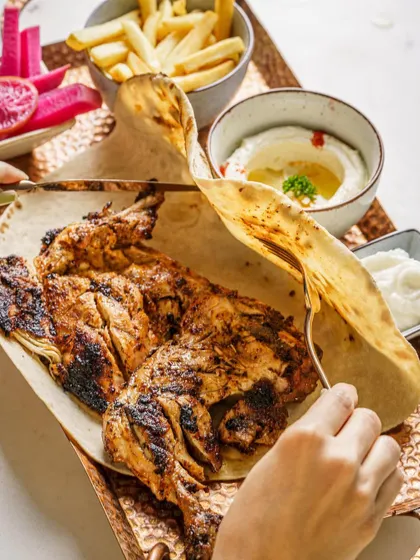 Capturing the action of tearing into a grilled chicken platter. This dynamic shot makes the food feel interactive and delicious, perfect for a casual dining restaurant.
