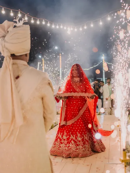 The bride's perspective. A beautiful shot of Priya walking towards Rahul for the varmala, her path lit by sparklers, creating a magical and romantic atmosphere.
