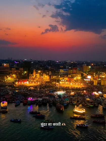 The city of Kashi, or Varanasi, glows with a spiritual energy as dusk settles over the Ganga. This aerial view captures the scale of devotion, with countless boats and people gathered for the evening aarti.
