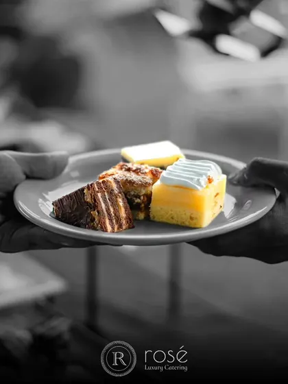 A selectively colored image of a server presenting a plate of assorted desserts. We believe in creating unforgettable experiences, from the first appetizer to the last sweet bite.