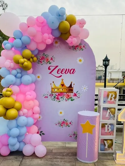 A royal princess-themed first birthday for Zeeva. This outdoor terrace setup includes a custom backdrop with a crown, a pastel balloon arch, and "BABY" blocks.