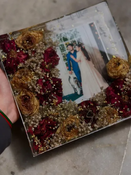 A square frame with a classic combination of red roses and baby's breath. The gold flakes add a touch of sparkle to this romantic and timeless wedding keepsake.