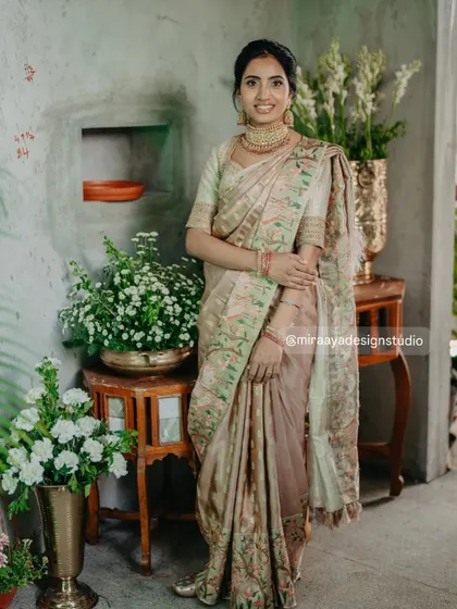 A full-length view of Nithya's beautiful ensemble. The custom-designed blouse perfectly complements her pastel-toned silk saree, creating a soft and elegant look.
