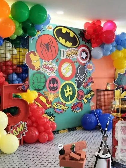 Another angle of the action packed superhero theme, showing the full extent of the colorful balloon garland and the variety of hero logos on the backdrop.