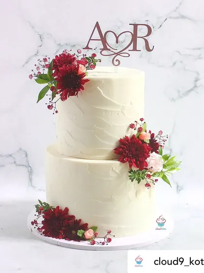 A beautiful two-tiered wedding cake featuring our custom rose gold monogram topper. The simple elegance of the topper complements the fresh flowers perfectly.