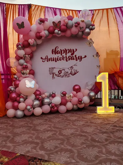 Celebrating a first anniversary with a custom backdrop in shades of pink and silver. This setup includes a personalized 'Happy Anniversary' graphic and a light-up number '1' to mark the special milestone.