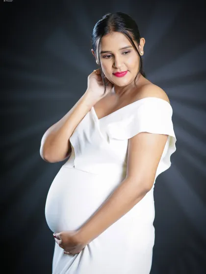 A delicate and thoughtful close-up portrait. The focus is on the mother-to-be's serene expression as she looks down, creating a feeling of quiet anticipation.