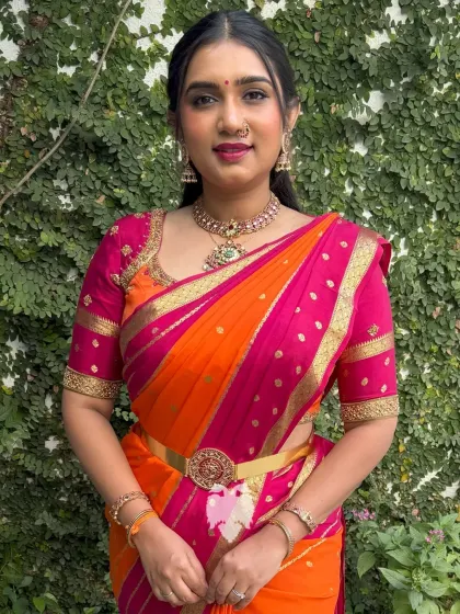A striking hot pink and orange silk blouse with intricate gold zari detailing and traditional motif embroidery.