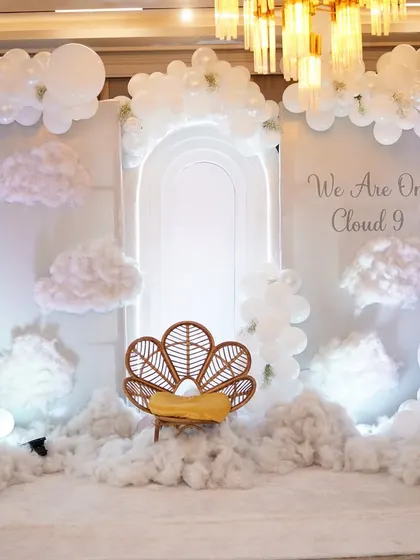 A dreamy, all-white 'On Cloud 9' baby shower theme. The fluffy clouds, white balloons, and neon arch created an ethereal and elegant atmosphere.