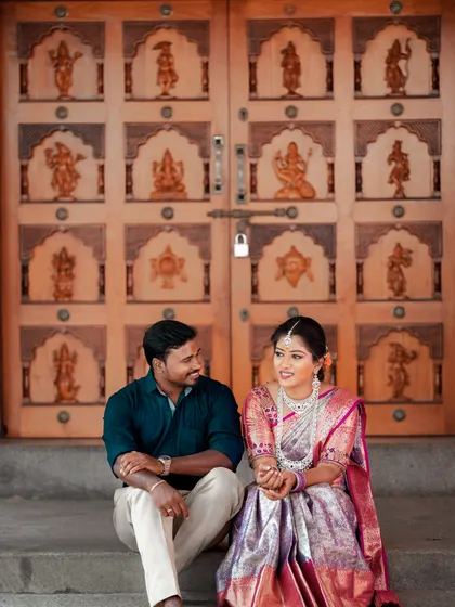 A seated portrait of the couple, providing a clear look at the bride's beautiful saree and jewelry.