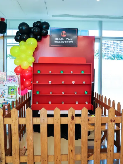The 'Dunk the Monsters' ball toss game, set up with a Deadpool theme for a superhero party.