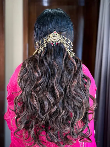 A stunning hairstyle for a 'Myrah' function, featuring long waves and a traditional, ornate hair accessory.