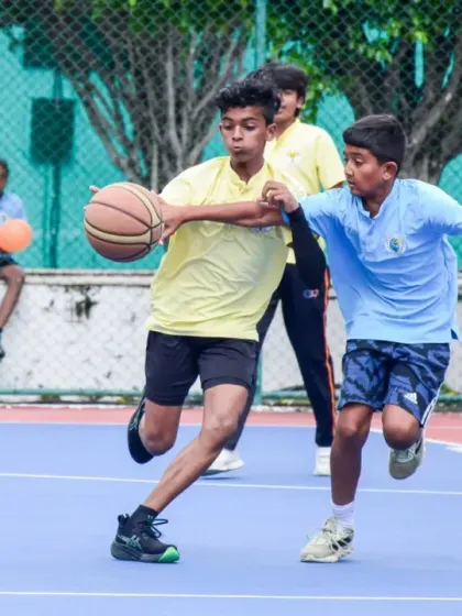 A player drives to the basket while being closely guarded, showing the determination and skill required to score.