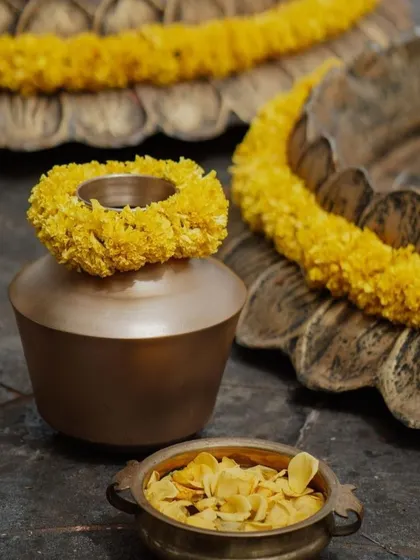 Close-up details of traditional Haldi decor, including brass pots and marigold garlands.
