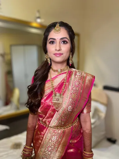 A full shot of the bride, her traditional pink silk saree complemented by soft, glowing makeup.