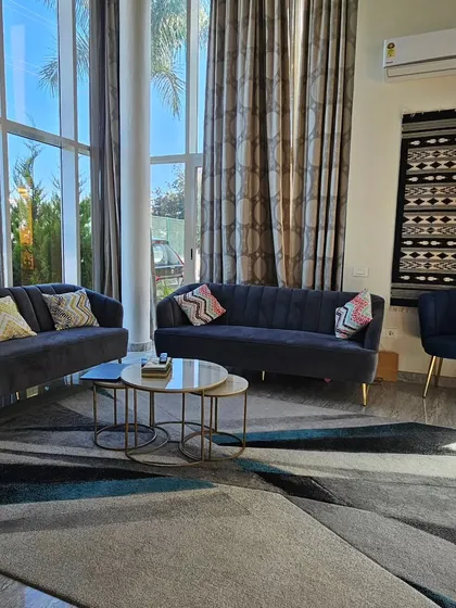 This is a completed living room in a Bangalore villa. The double-height windows bring in ample natural light, and I've used a combination of comfortable sofas and accent chairs to create a welcoming space for the family.