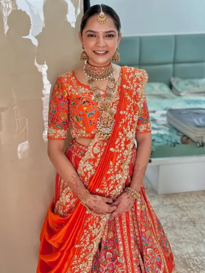 The bride looks stunning in her orange lehenga, her hair styled in a chic and elegant floral bun.