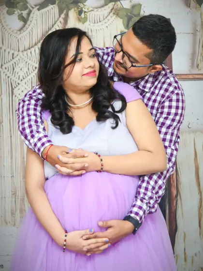 A candid and loving moment between a couple during their studio maternity session. The partner's embrace from behind is a popular and heartfelt pose.