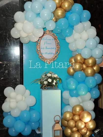 A welcome sign and balloon arch in shades of blue, white, and gold, creating a festive and inviting entrance for the prince's first birthday party.