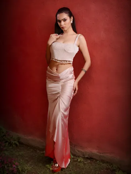 This full-length view shows the complete custom look for Miss Earth 2023, a perfect blend of modern glamour and timeless grace against a dramatic red backdrop.