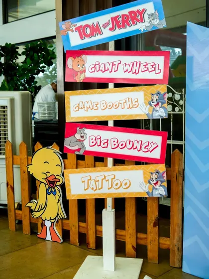 A fun directional sign for a Tom & Jerry party, guiding guests to the 'Giant Wheel', 'Game Booths', and 'Big Bouncy'.