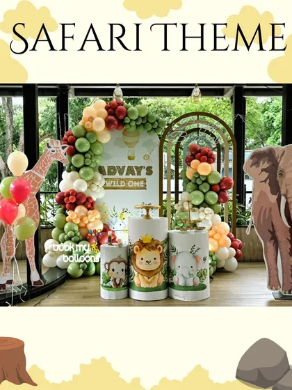 We created a wild adventure for Advay's first birthday with this safari theme. The setup included large giraffe and elephant cutouts, a lush balloon arch in green and red, and adorable animal characters on the pedestals.
