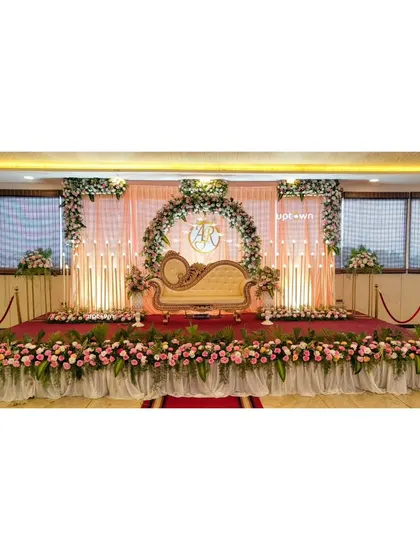 A beautiful engagement stage with a pink and white floral arch and elegant candle-like lights.