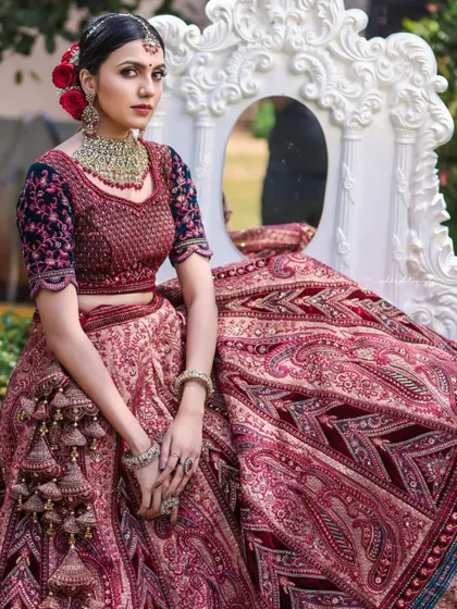An outdoor shoot for a rental clothing brand, featuring a model in an opulent maroon and navy bridal lehenga. The images are framed to highlight the grand design of the outfit.