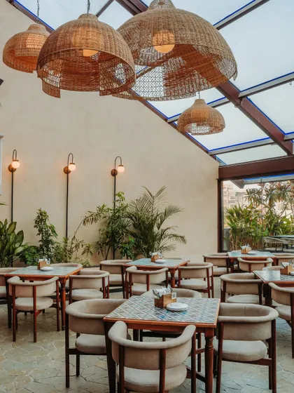 The dining area under the skylight is bright and airy, filled with natural light. I used large, woven rattan pendant lights and comfortable, neutral-toned chairs to create a relaxed, al fresco dining feel indoors.